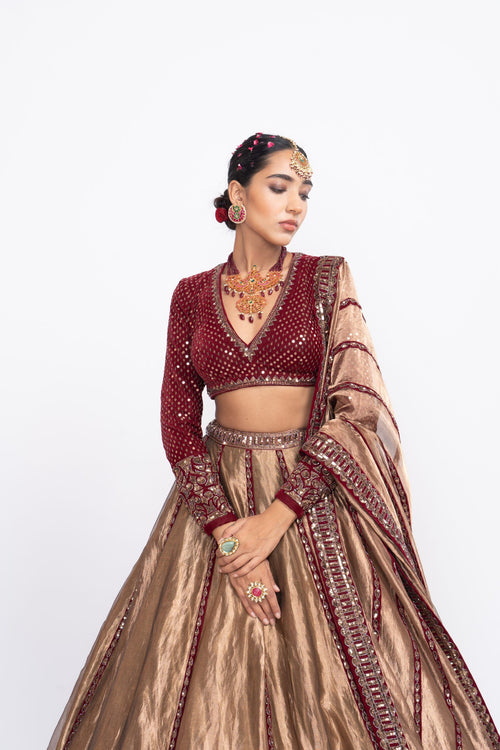 Mehroon embroidered blouse paired with copper tissue lehenga.